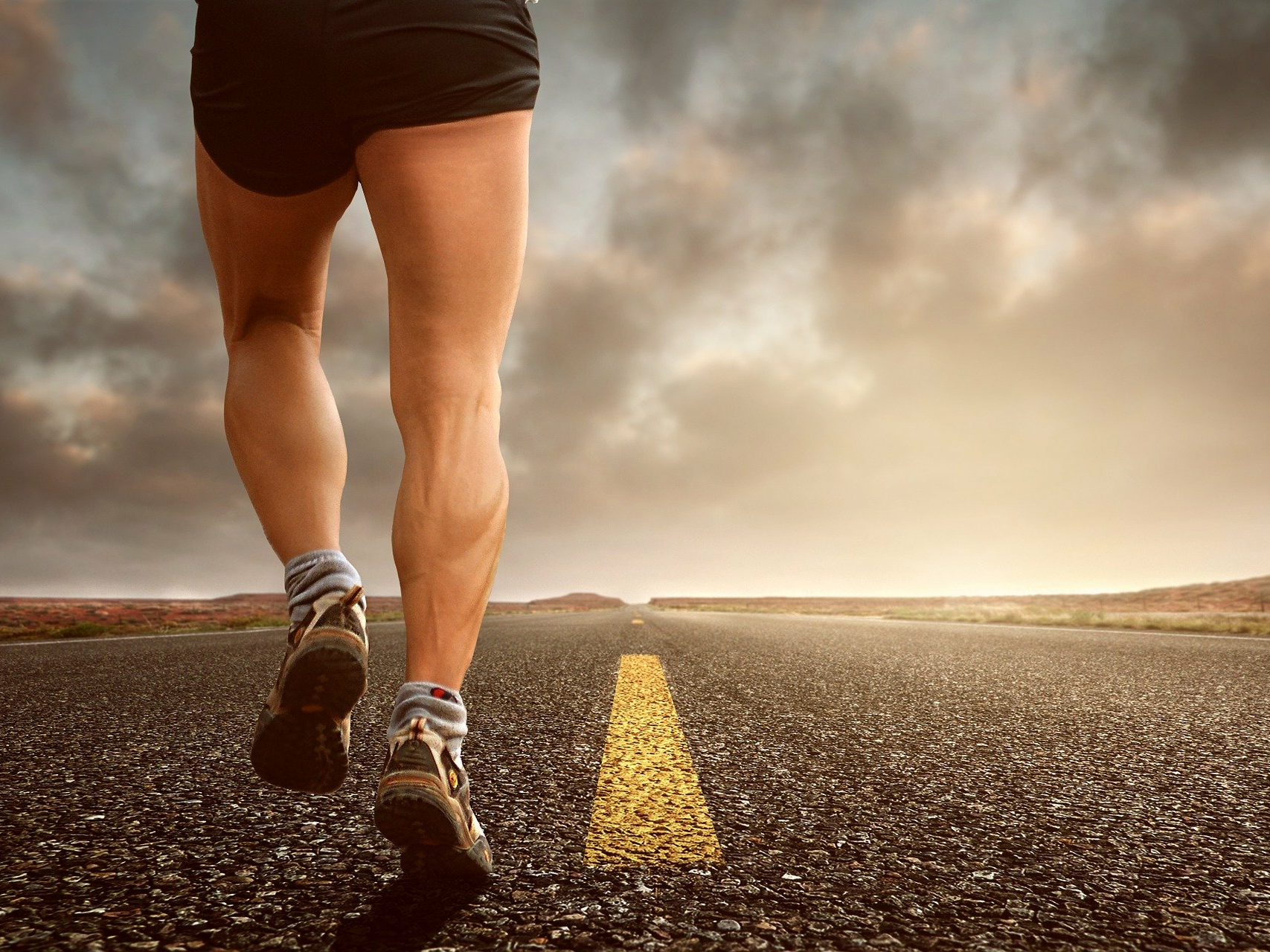 Beine eines Läufers, der eine asphaltierte Straße entlang läuft. Brand Driven Transformation ist ein Marathon.